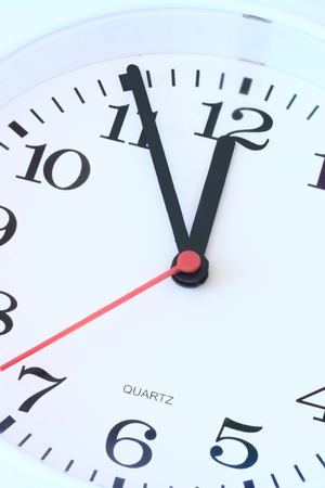 Wall clock dial close-up, five minutes to twelve