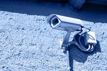 Security camera mounted on stone wall toned in blue