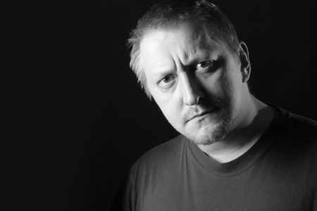 Serious man looking at camera over dark background with space for text on left. Black and white image.の写真素材