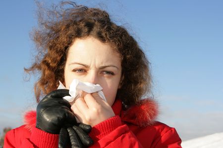 Young woman blowing her nose at tissue