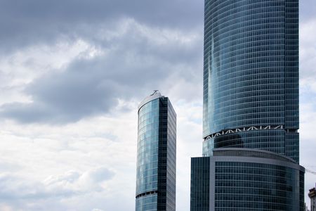 Two modern skyscrapers against sky with clouds