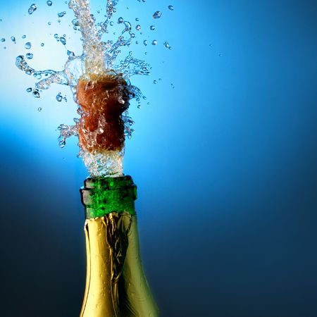 Bottle of champagne with splashes over blue backgroundの写真素材