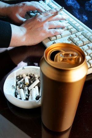 Beer can, ash tray and man working at night