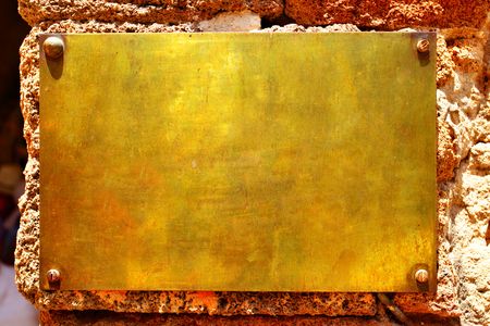 Blank copper signboard close-up over stone wallの写真素材