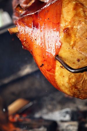 Grilled pig leg on spit close up