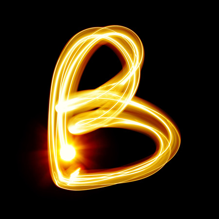 B - Created by light alphabet over black backgroundの写真素材