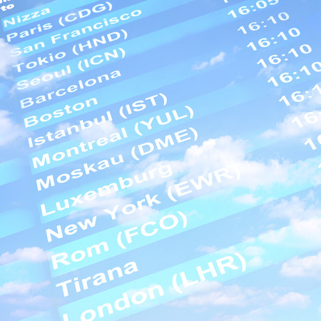 Flight information board against blue sky with clouds