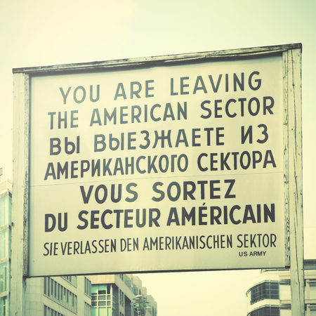 You are leaving the american sector - Historic sign near The Checkpoint Charlie in Berlin, Germany. Retro styleの写真素材