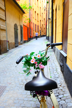 Bicycle with daisy flowers on handle bar in old street in Stockholm, Swedenの写真素材
