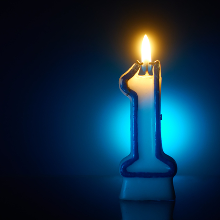 Number One - Burning birthday candle on blue backgroundの写真素材