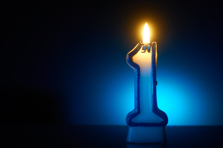 Number One - Burning birthday candle on blue backgroundの写真素材