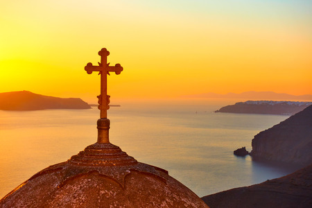 The dome with cross of a Greek orthodox church in Thira town in Santorini Island at sundown, Greeceの写真素材
