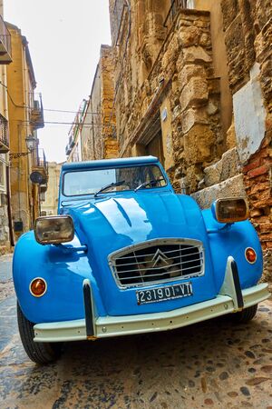 Cefalu, Italy - March 19, 2019: Angle shot of retro car Citroen 2CV parked in the old street
