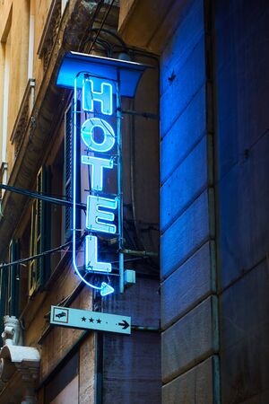 Blue neon hotel sign with arrow on the wall close-upの写真素材