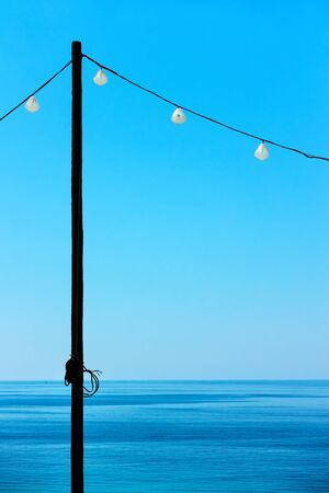 Seascape with sea horizon, clear blue sky and decorative string of holiday lights - Minimalistic background with space for textの写真素材