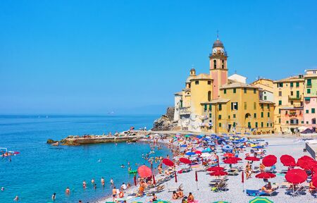 Camogli, Genoa, Italy - July 3, 2019:  Beach with resting people near old church in Camogli on sunny summer dayのeditorial素材