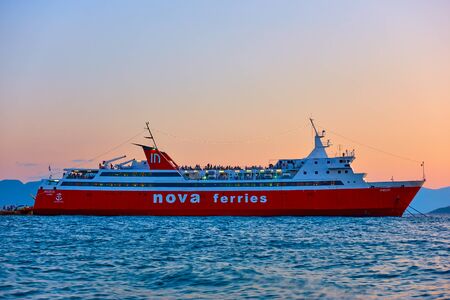 Aegina, Greece  - September 15, 2019: Ferryboat at the port of Aegina at twilight. Ship: Nova...