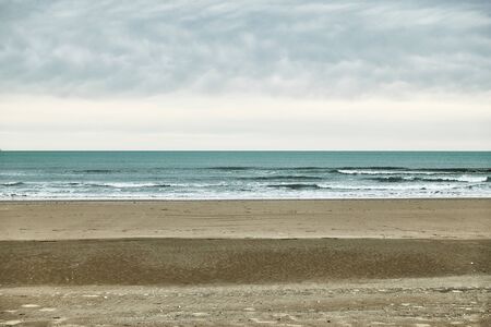 Minimalistic striped landscape with sandy beach, sea and cloudy skyの写真素材