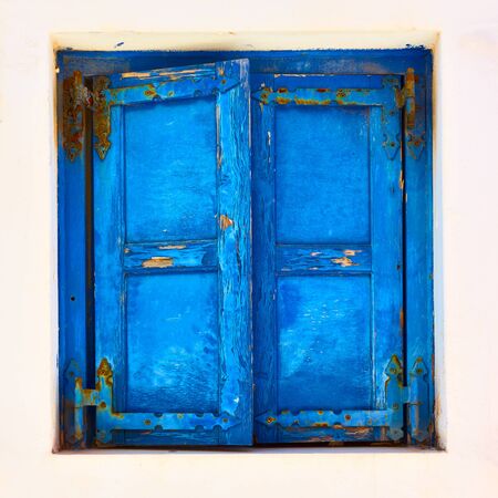 Window of greek whitewashed house with closed trditional blue shutters in Mykonos island, Greeceの写真素材