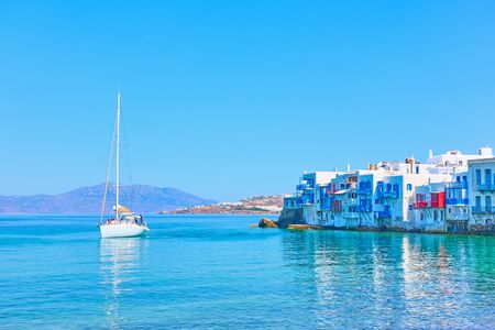 Idyllic greek landscape with houses by the sea in Mykonos Island and sail yacht, Greeceの写真素材