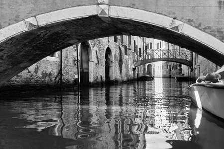 Perspective of canal with bridges in Venice, Italy. Black and white photography, venetian cityscapeの写真素材