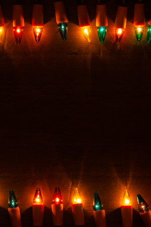 Christmas Lights - Strings of vintage multicolored light bulbs on dark wooden background with space for textの写真素材