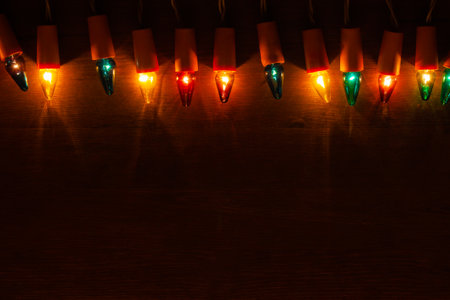Christmas Lights. Retro light bulbs of different colors on dark wooden background with copy spaceの写真素材