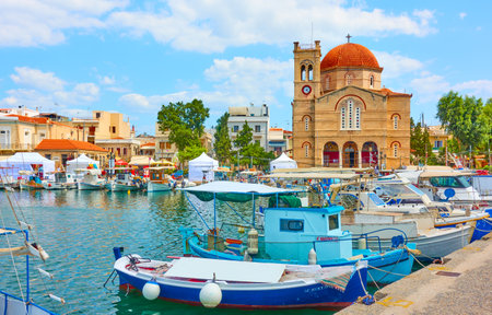Aegina, Greece - September 13, 2019: View of Aegina town with Ekklisia Isodia Theotokou Church and moored fshing boatsのeditorial素材