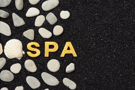 Spa word in black sand with pebbles. Background with space for your own textの写真素材