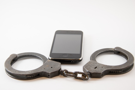 locked phone. phone locked with handcuffs on white background.の写真素材