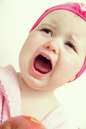 Baby holding and eating an apple, isolated on whiteの写真素材