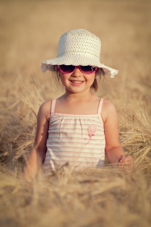 Happy girl in the field of wheat on sunny dayの写真素材