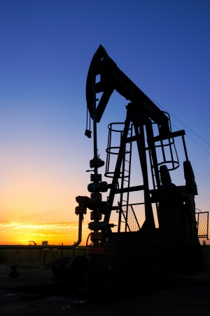 An oil pump jack is silhouetted by the setting sunの写真素材