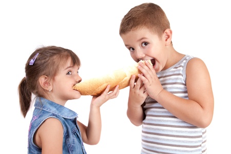 beautiful little girl and boy eats bread with chocolate creamの写真素材