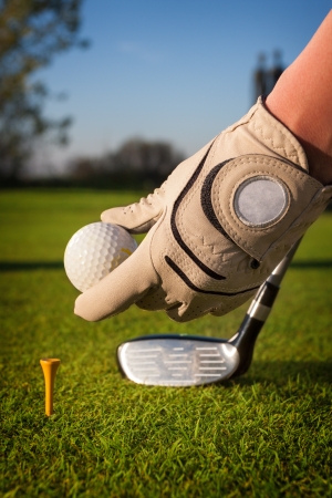 Hand hold golf ball with tee on courseの写真素材