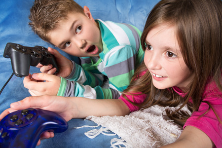 Happy children - girl and boy playing a video game