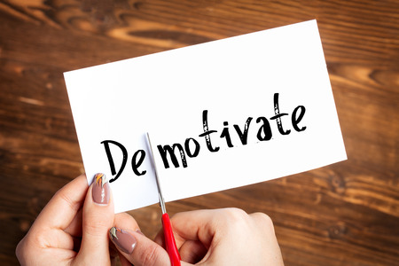 Woman hands cutting card with the word demotivateの写真素材