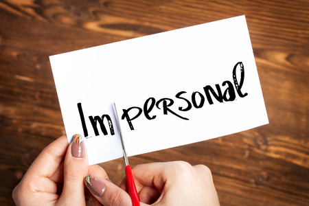 Woman hands cutting card with the word impersonalの写真素材