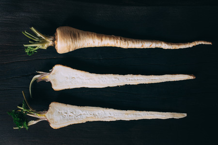 Fresh parsley roots on wooden cutting board