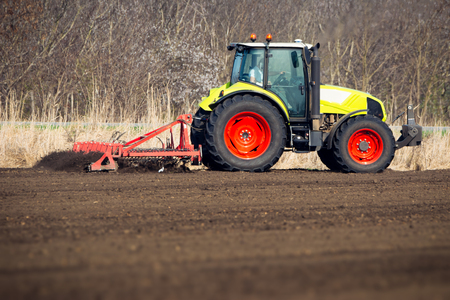 Farmer in tractor preparing land with seedbed cultivatorの写真素材
