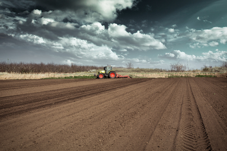 Farmer in tractor preparing land with seedbed cultivator