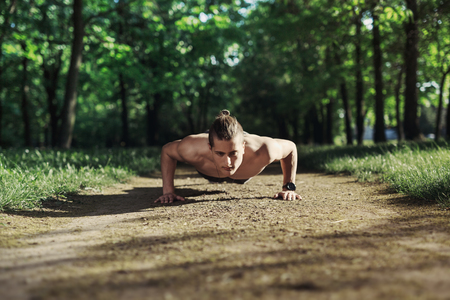 Young athletic man doing push-ups. Muscular and strong guy exercising.の写真素材