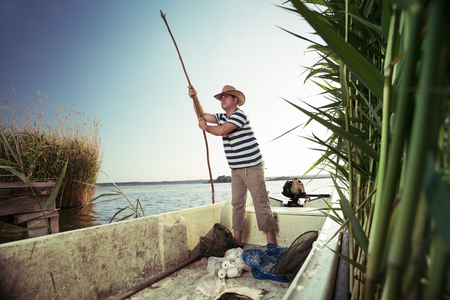 Fisherman pushing boat from the river bankの写真素材