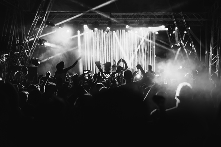 Silhouettes of people at a concert in front of the scene in bright light. Black and Whiteの写真素材