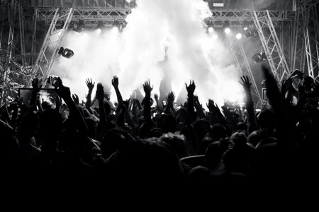 Silhouettes of people at a concert in front of the scene in bright light. Black and Whiteの写真素材
