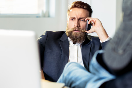 Hipster businessman relaxing at his desk in his officeの写真素材