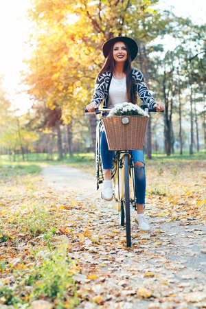 Happy woman riding bike bicycle in fall autumn parkの写真素材