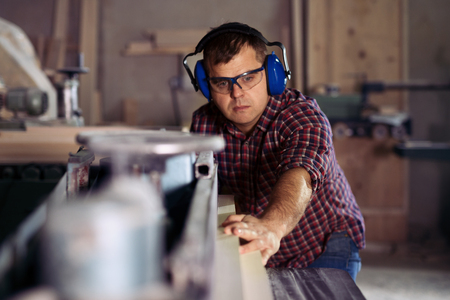 Carpenters cutting wooden plank with a circular sawの写真素材