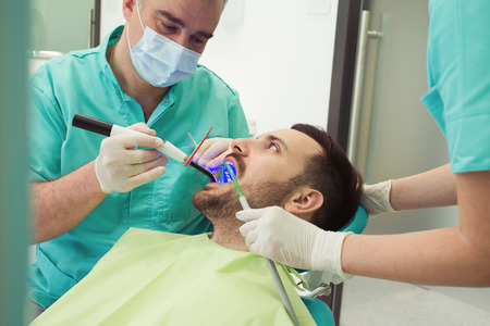 Dentists examining and working on male patient.Dentist's office.の写真素材