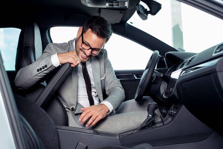Handsome businessman is sitting in a new car in car dealershipの写真素材